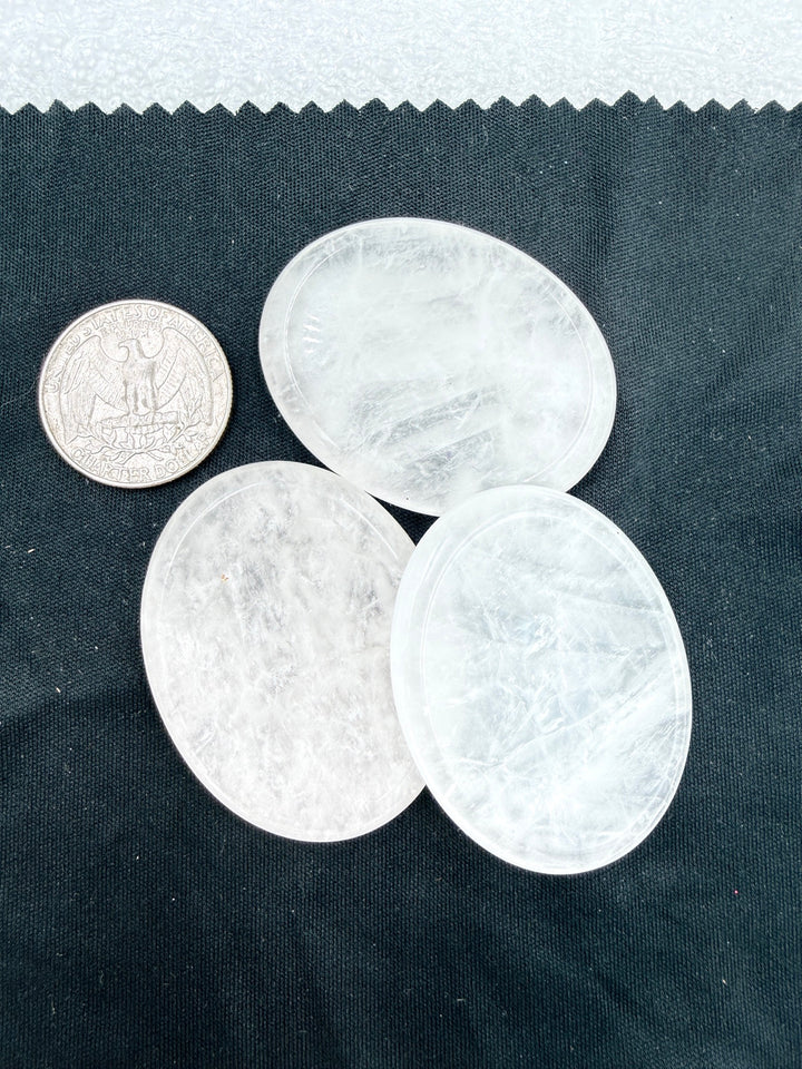 Three clear quartz comfort stones with a quarter for scale