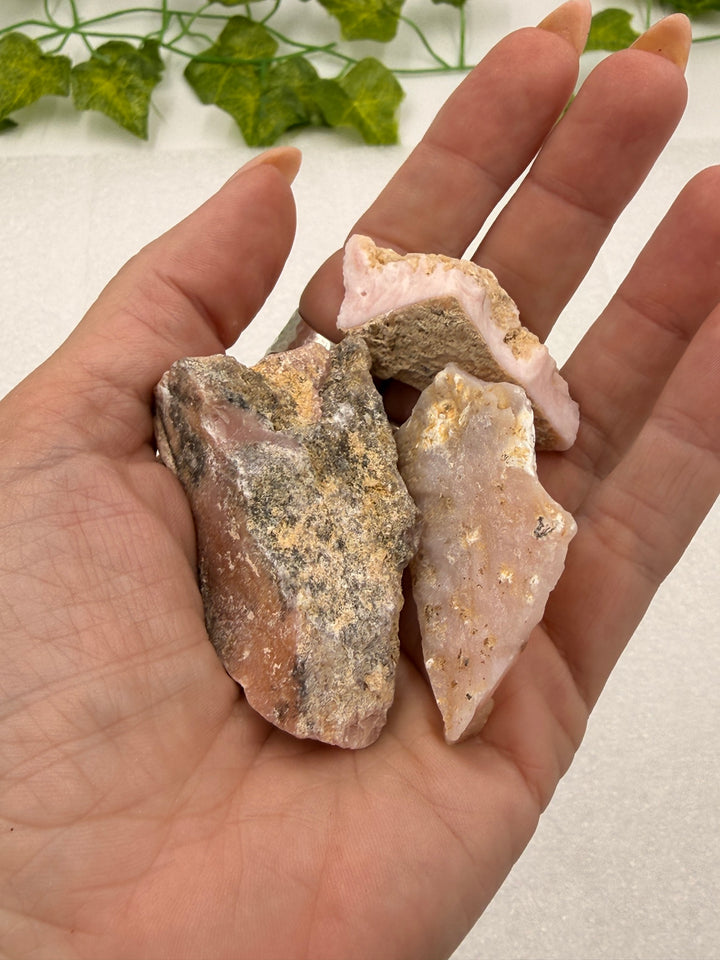 Cherry opal rough pocket stones held in hand