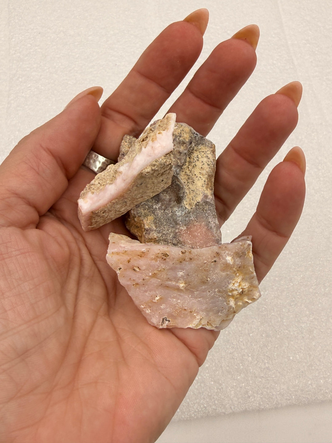 Cherry opal rough pocket stones in an open palm