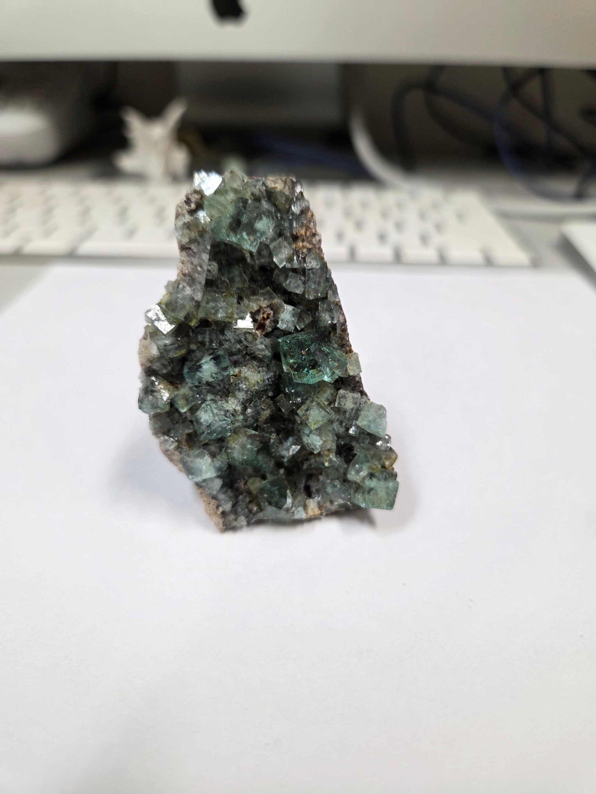 Green Fluorite Specimen with triangular crystalline structure and vibrant green hues on white surface