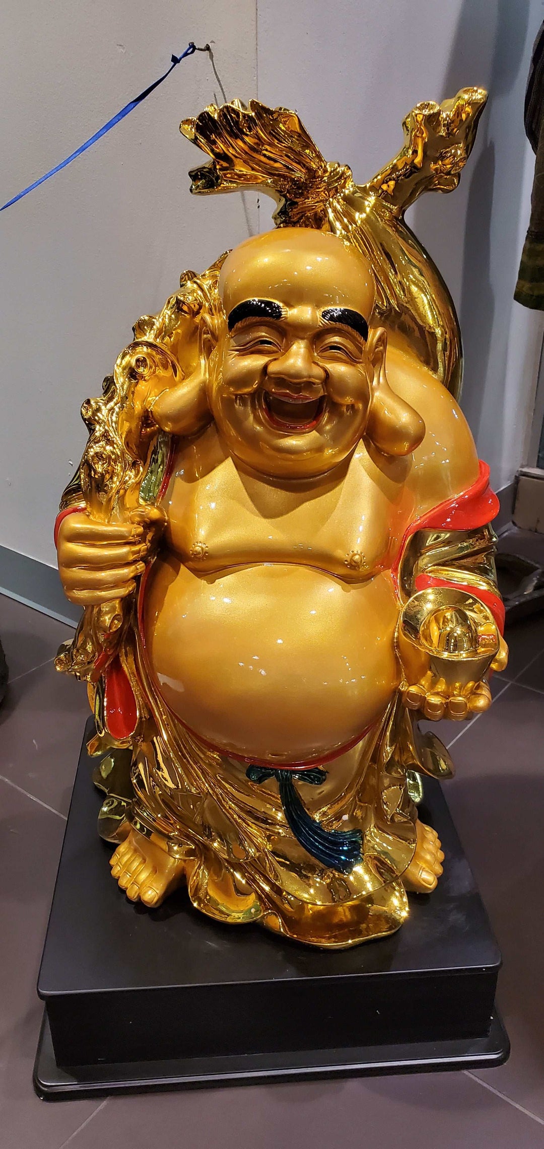 Happy Buddha statue of abundance on raised platform, gold color, over 2 feet tall.